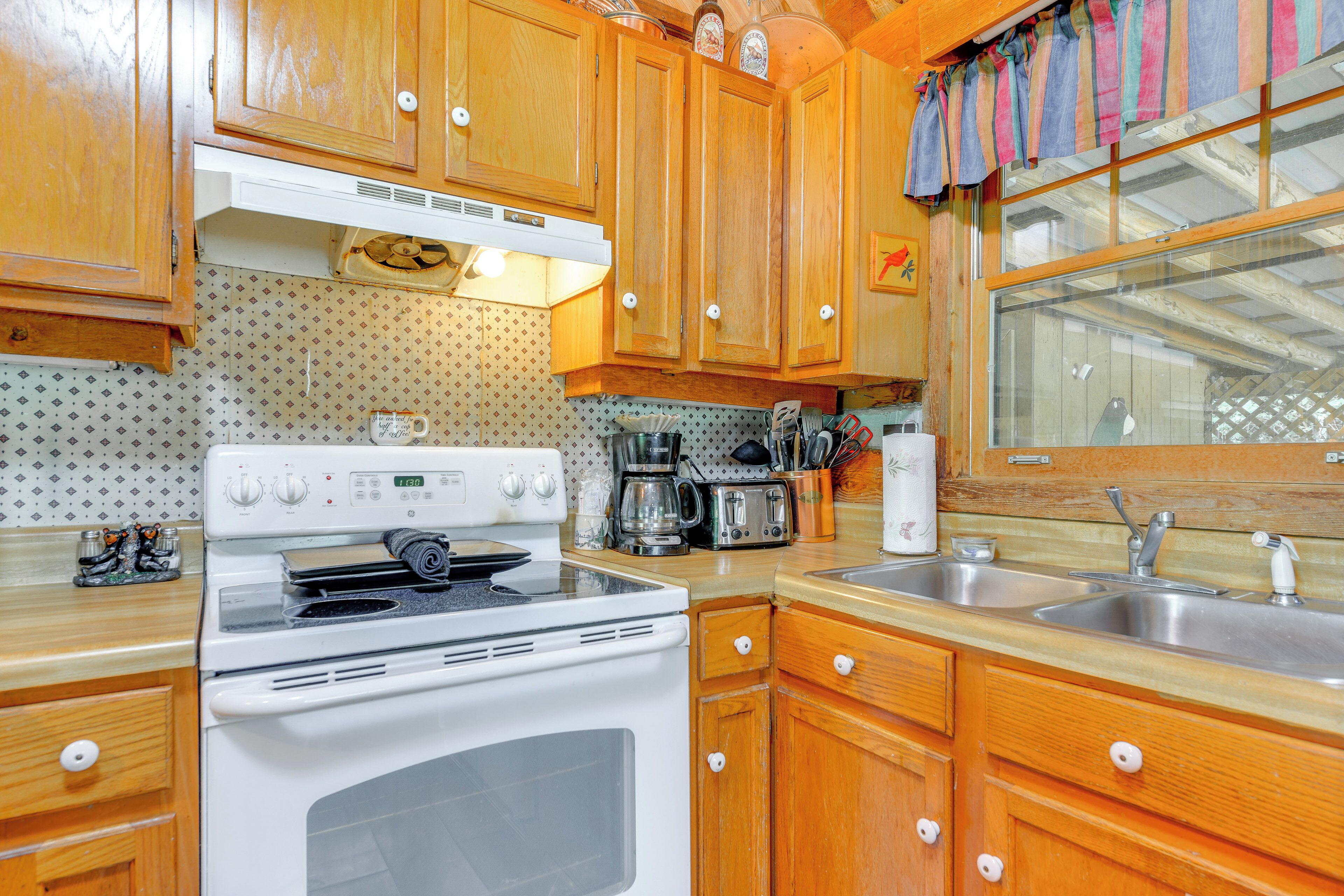 A kitchen with wooden cabinets, a white stove, a sink, and various appliances.