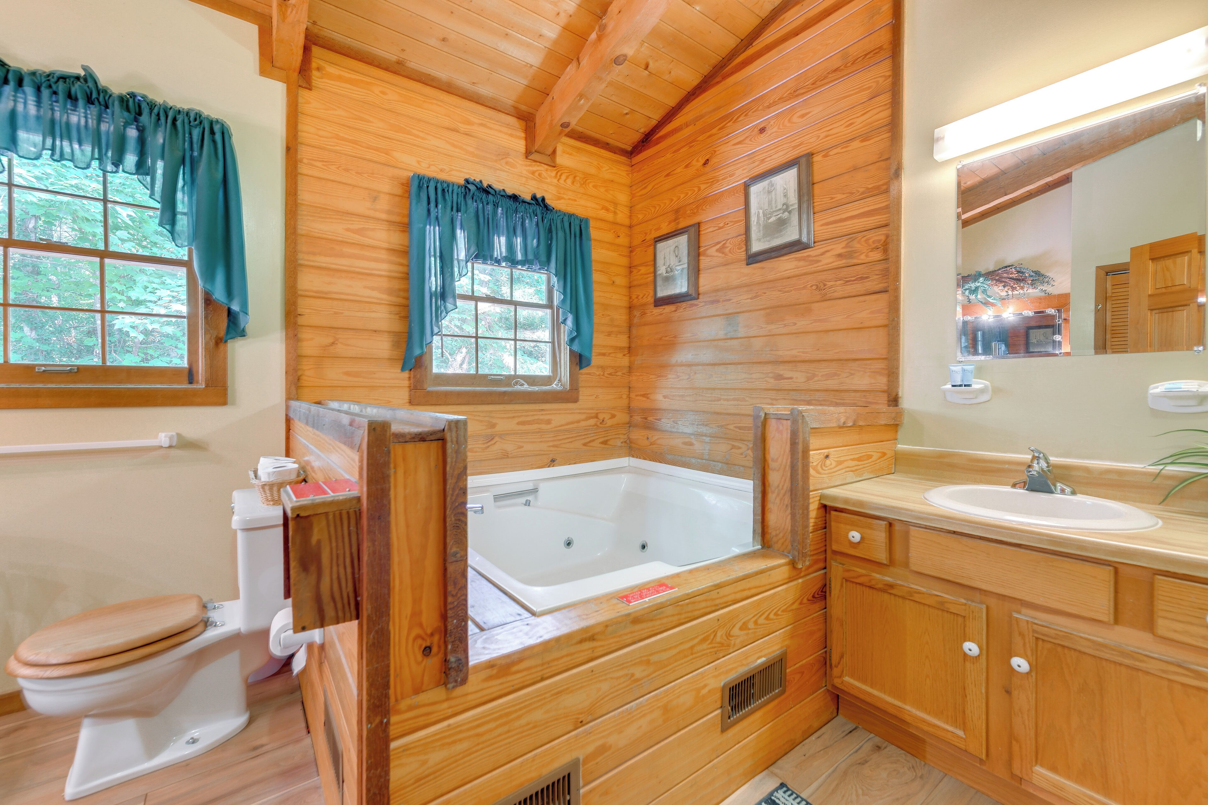 Ein Badezimmer einer Holzhütte mit Toilette, Badewanne, Waschbecken und Spiegel.