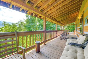 Eine Holzterrasse mit überdachtem Bereich, Gartenmöbeln und Blick auf Grünflächen.