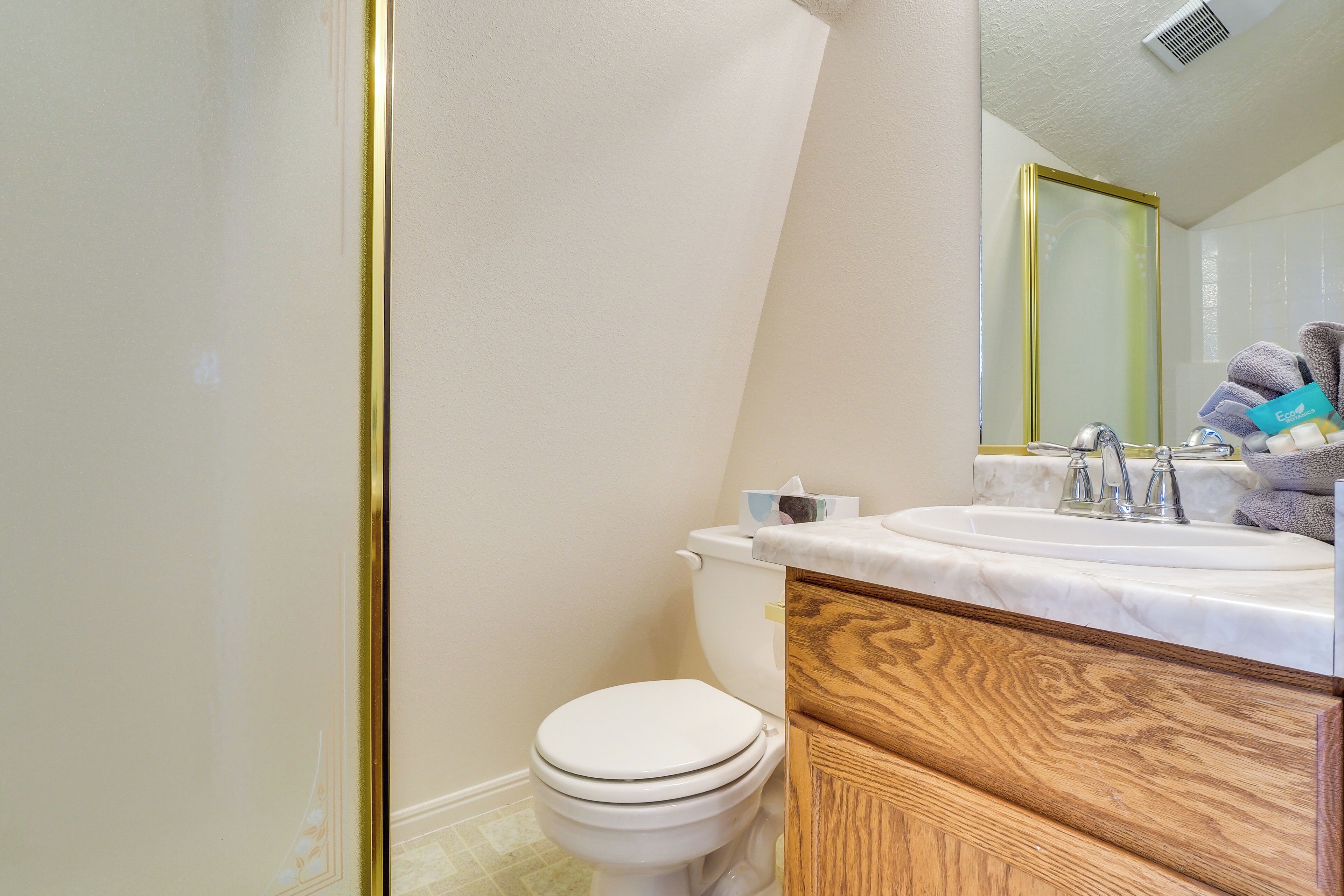 A bathroom with a toilet, sink, and wooden vanity.