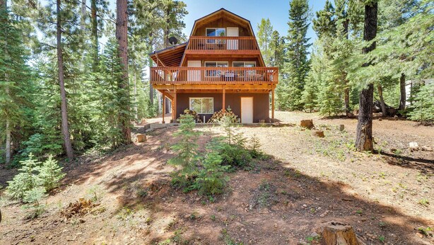 Eine zweigeschossige Holzhütte mit einem Balkon, umgeben von einem Wald.
