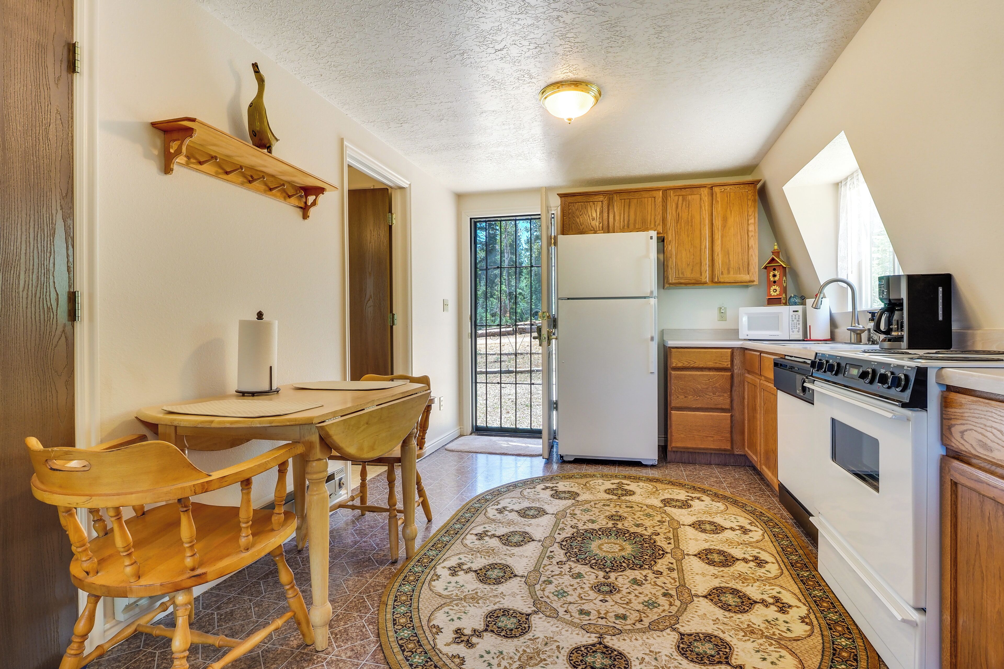A compact kitchen with wooden cabinets, a refrigerator, a stove, and a dining area with a table and chairs.