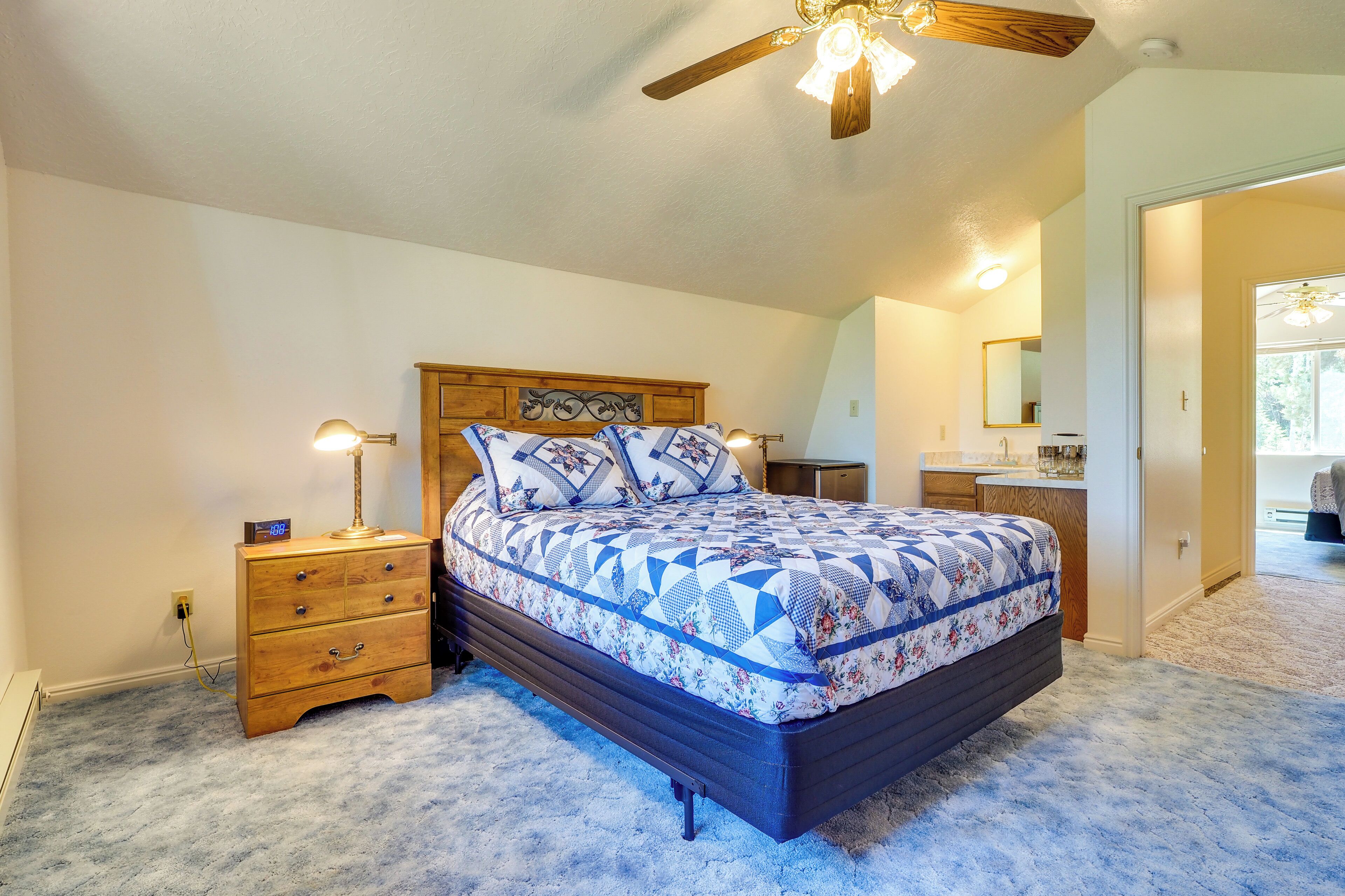 A bedroom with a wooden bed, a nightstand, a dresser, and a ceiling fan.