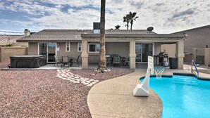 Ein Wohnhaus mit Schwimmbad, Terrassenmöbeln und einer überdachten Sitzgruppe im Freien.