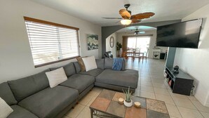 Ein Wohnzimmer mit einem Ecksofa, einem Couchtisch und einem flachbildfernseher an der Wand.