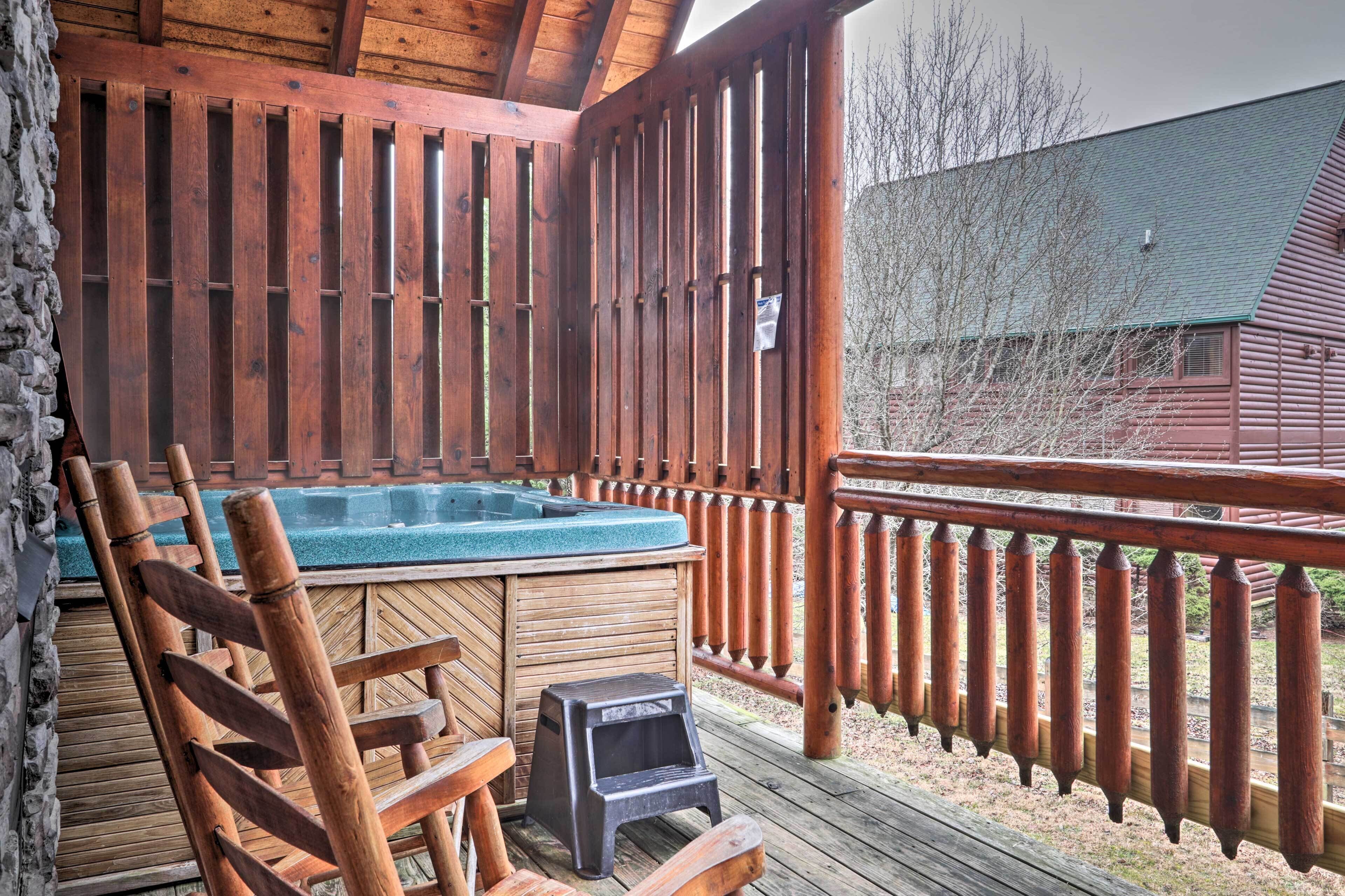 Een houten terras met een jacuzzi, houten stoelen en een klein krukje.