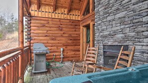 Een houten blokhut met een stenen openhaard, een barbecue en een jacuzzi.