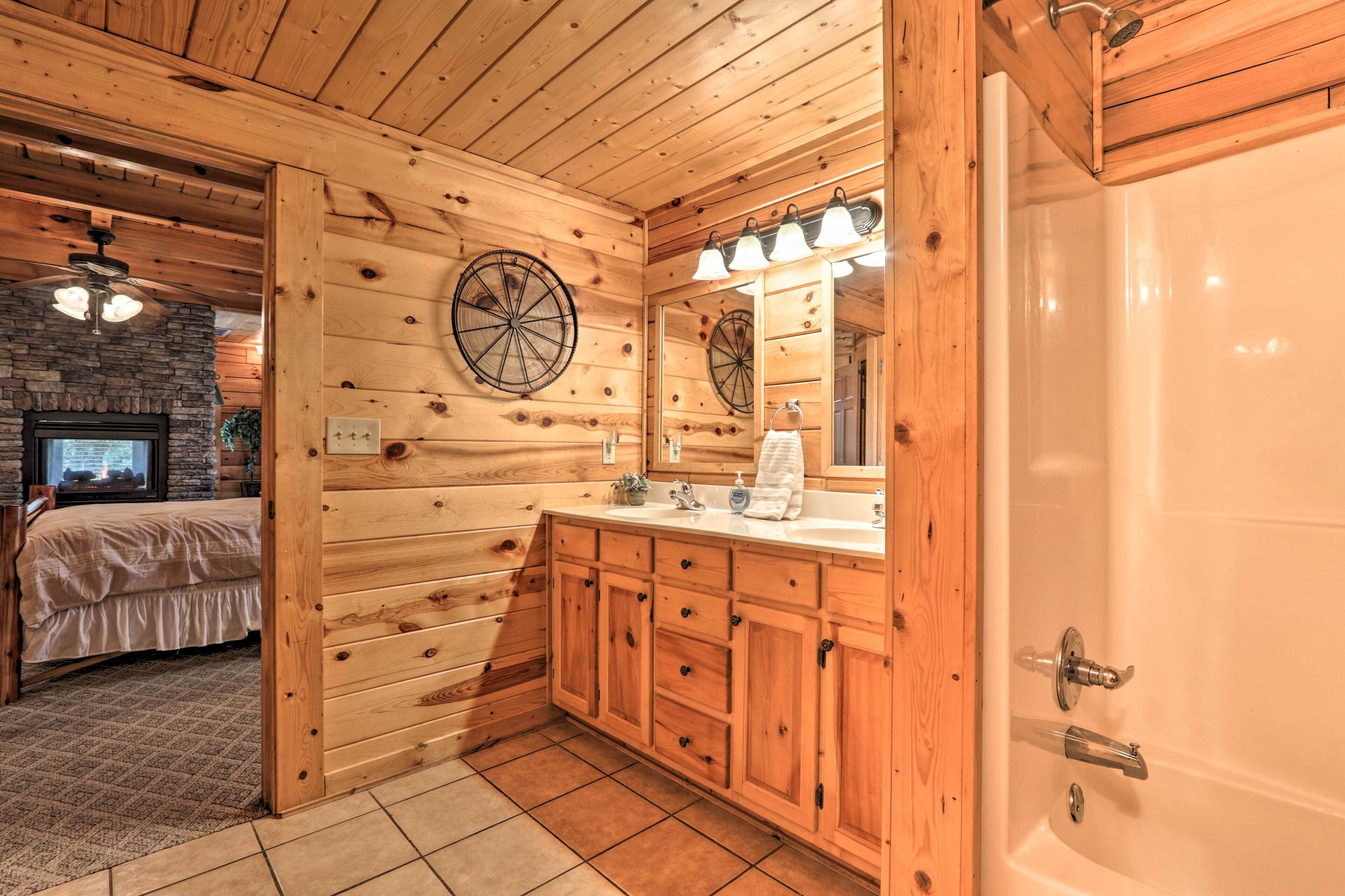 Un baño de cabaña de madera con un espejo grande, armarios de madera, un lavabo y una ducha.
