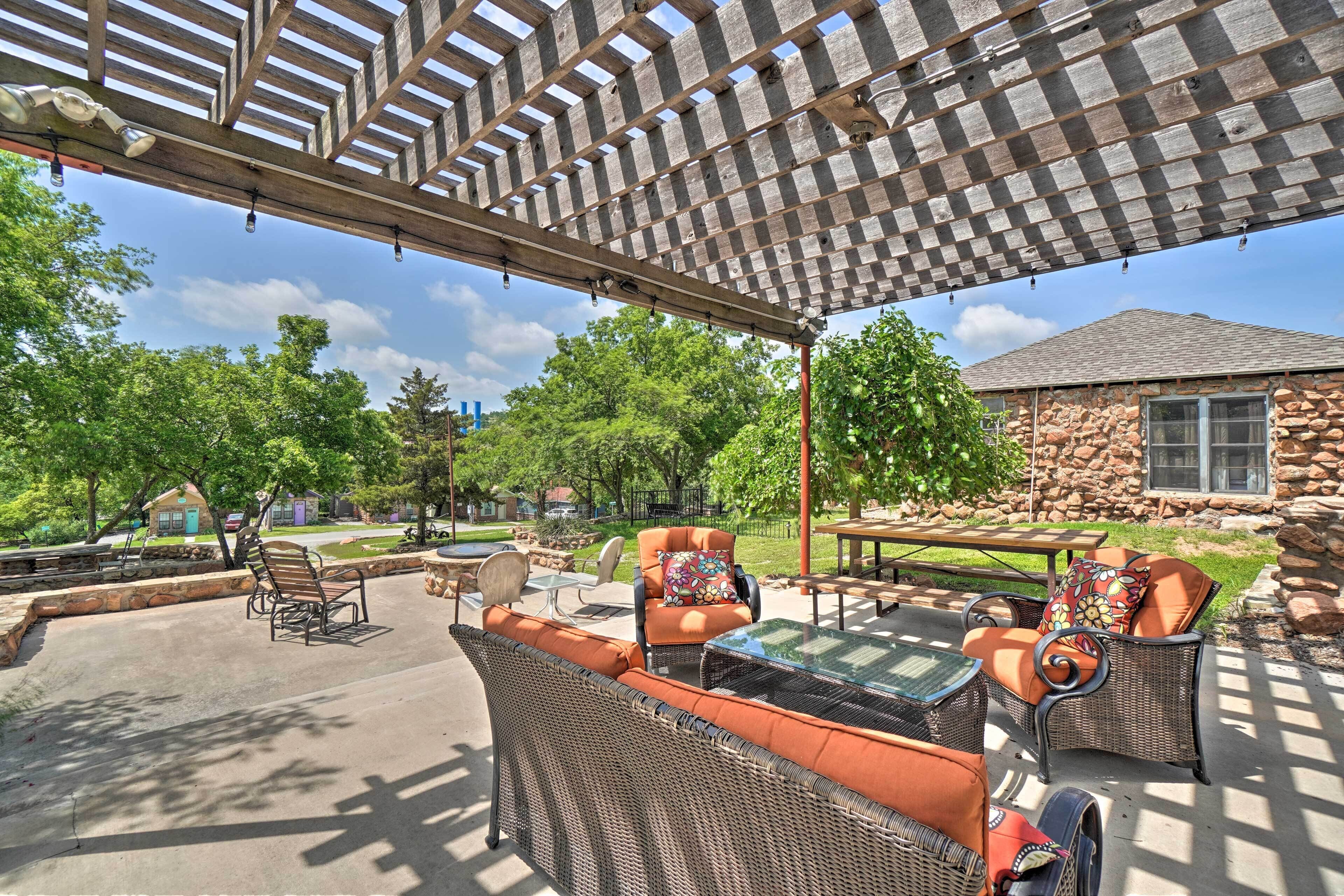 An outdoor patio with wicker furniture, a stone building, and a pergola.