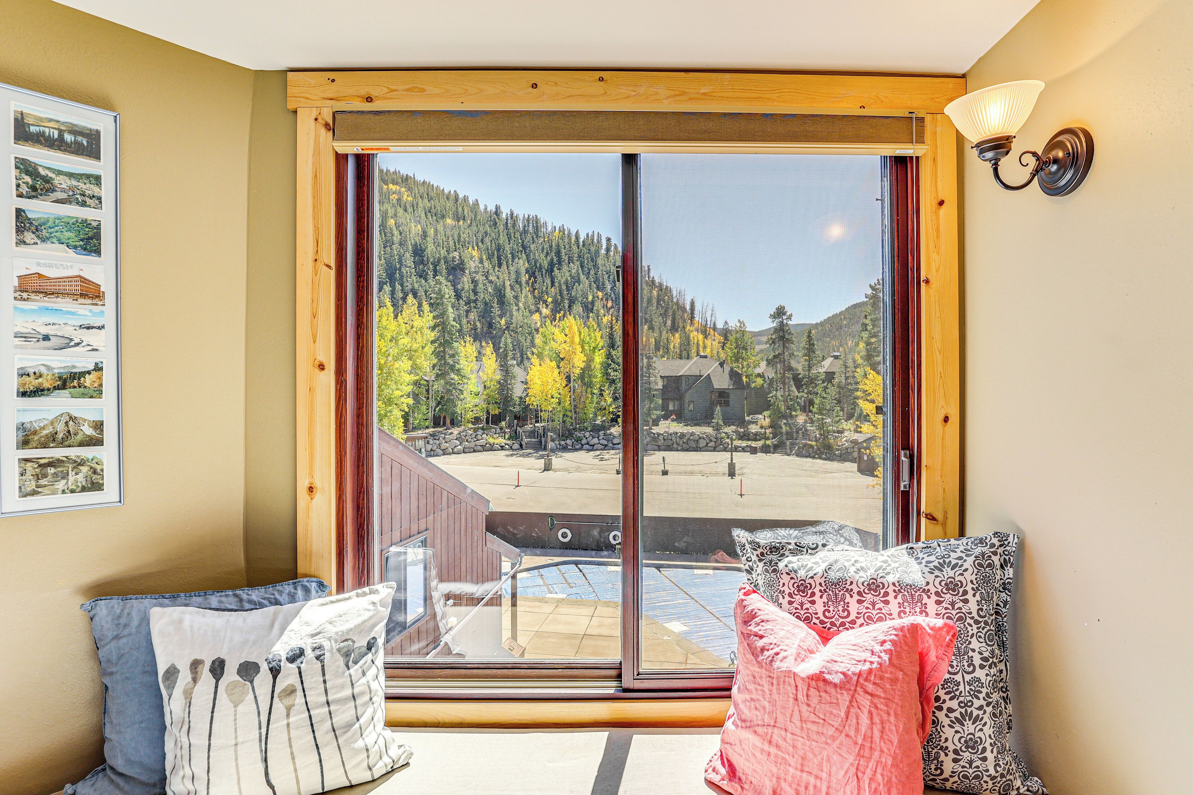 A room with a large sliding glass door leading to a balcony with a mountain view.
