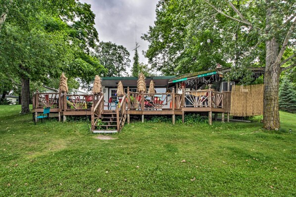 Un chalet rustique doté d’une terrasse en bois, entouré d’une végétation luxuriante.