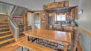 A spacious kitchen with wooden cabinetry, a large central island, and a rustic wooden staircase.