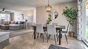 A modern living room with a sectional sofa, dining table, and chairs. There is a large mirror on the wall and a hanging light fixture. - Duplex w/ Private Yard: 3 Mi to Downtown Loveland! (Loveland)