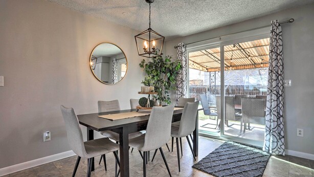 A dining area with a round mirror, a hexagonal pendant light, and a dining table with chairs. - Duplex w/ Private Yard: 3 Mi to Downtown Loveland! (Loveland)