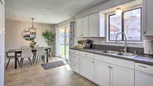 A modern kitchen with white cabinets, a granite countertop, and a large window providing natural light. - Duplex w/ Private Yard: 3 Mi to Downtown Loveland! (Loveland)