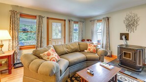 A cozy living room with a sectional sofa, a fireplace, and large windows with curtains. - Upper Valley Retreat on 15 Acres Near Dartmouth (Meriden)