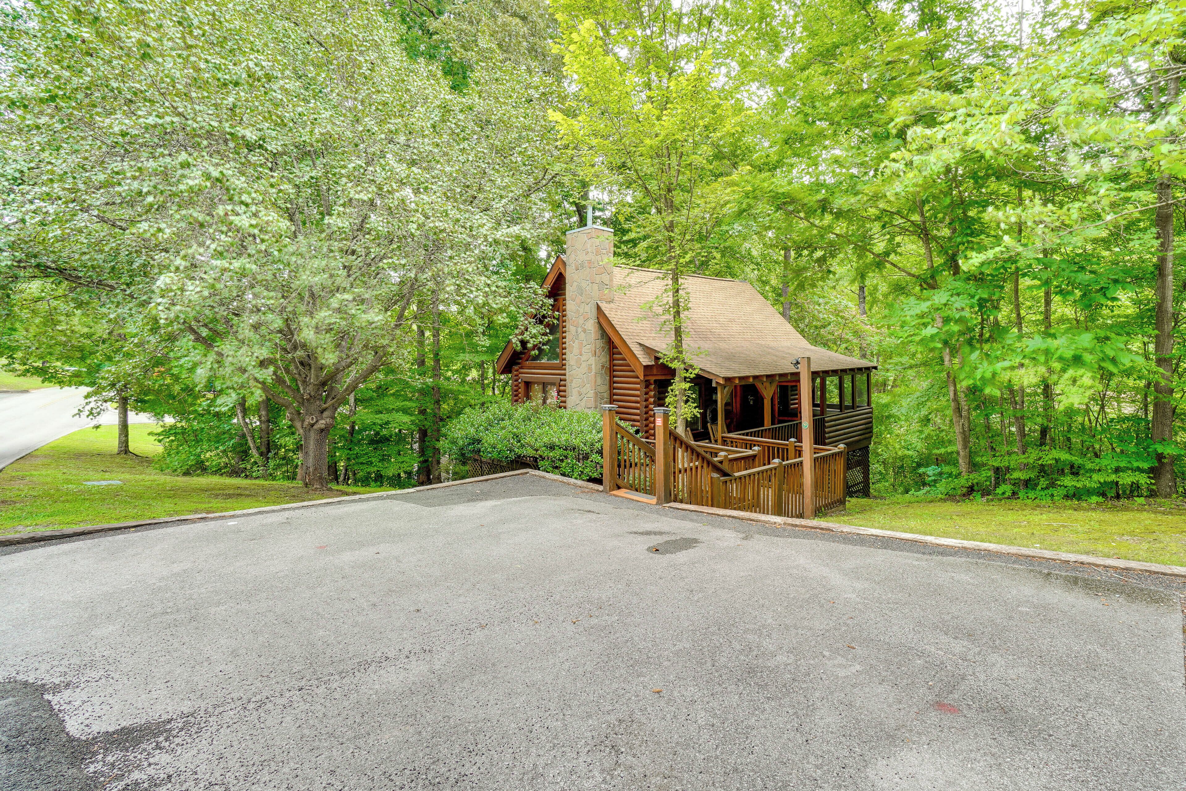 A log cabin with a stone chimney, surrounded by dense forest.