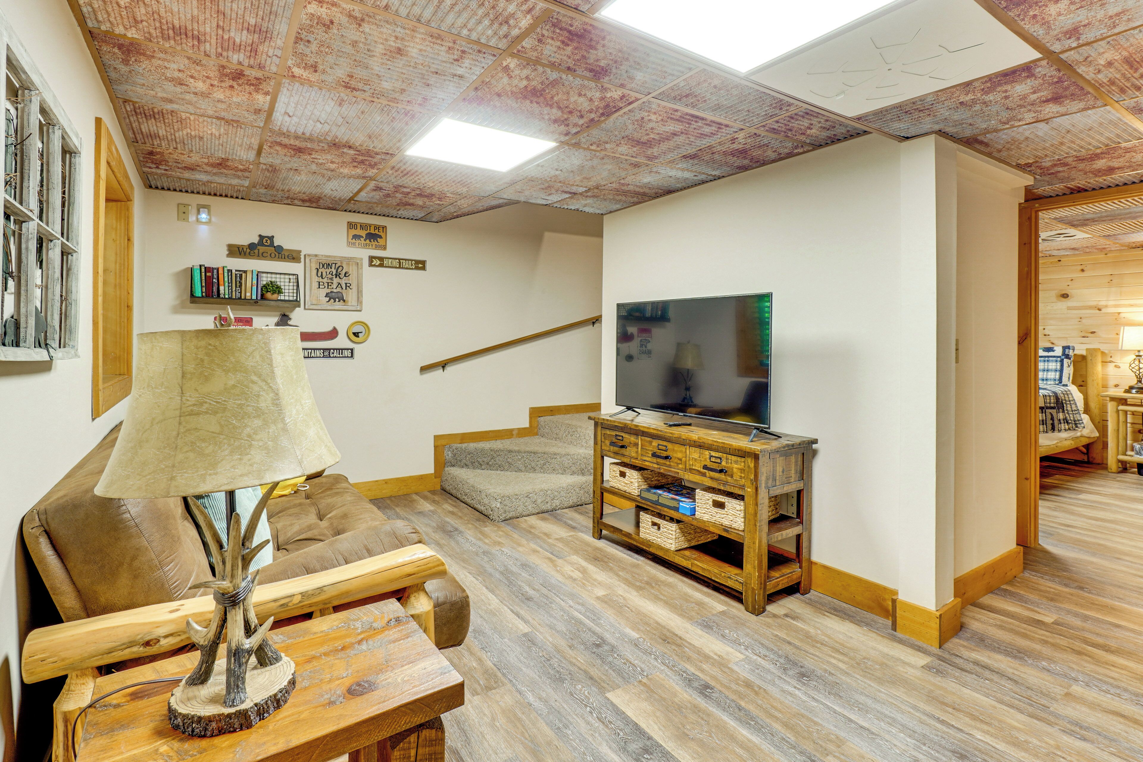 Un salon avec un téléviseur, des meubles en bois et un escalier.