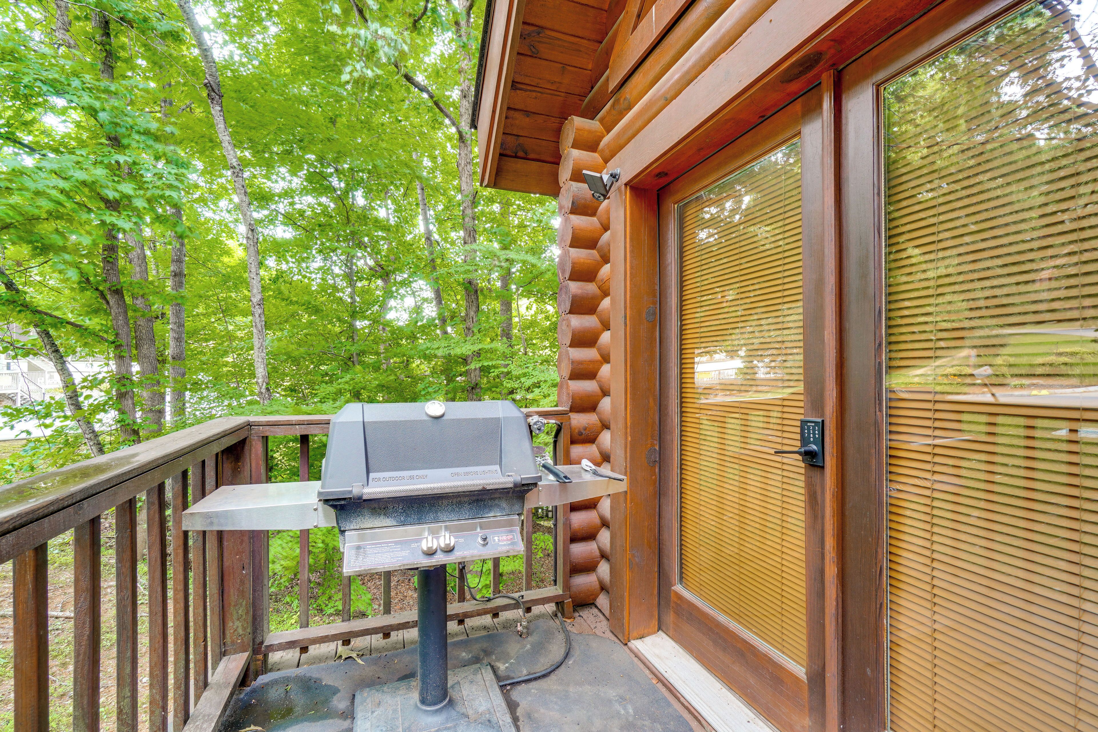 A wooden deck with a grill, a glass door with blinds, and a wooden railing.