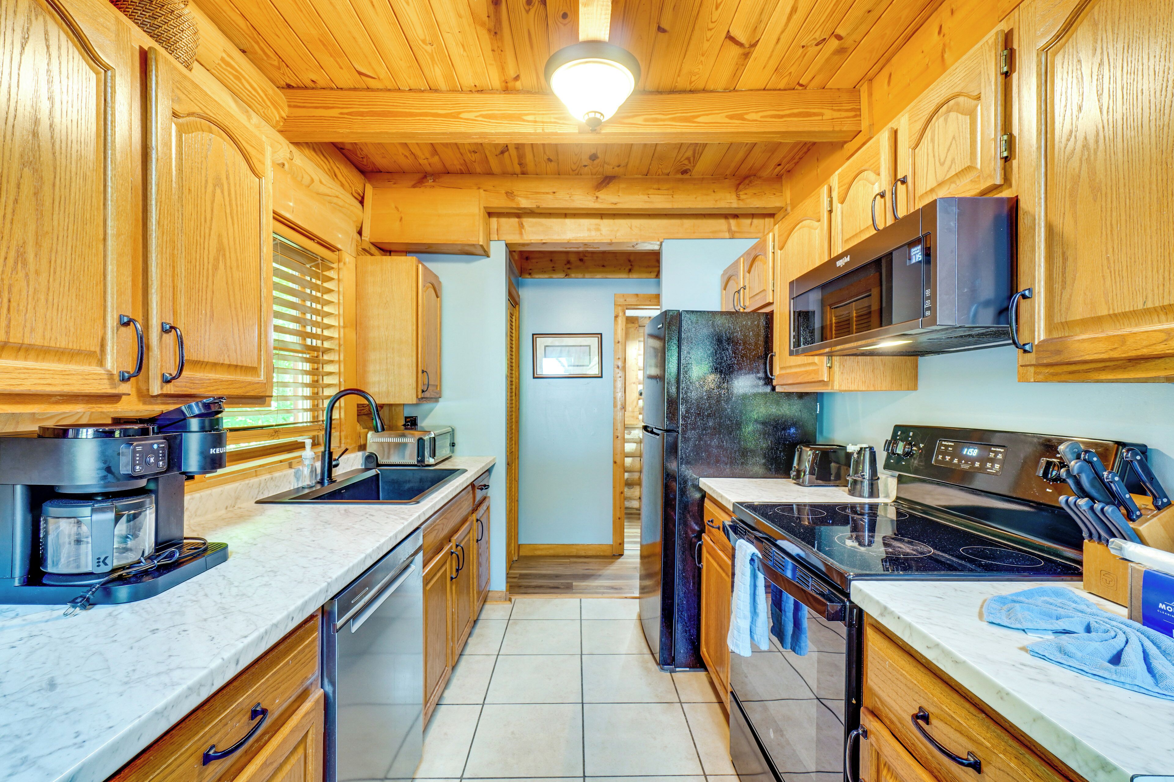 A kitchen with wooden cabinets, a microwave, a refrigerator, and a stove.