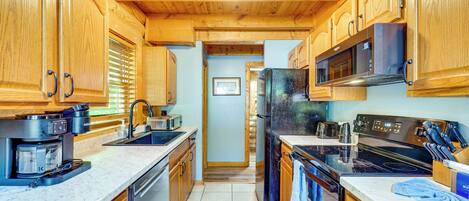 A kitchen with wooden cabinets, a microwave, a refrigerator, and a stove.