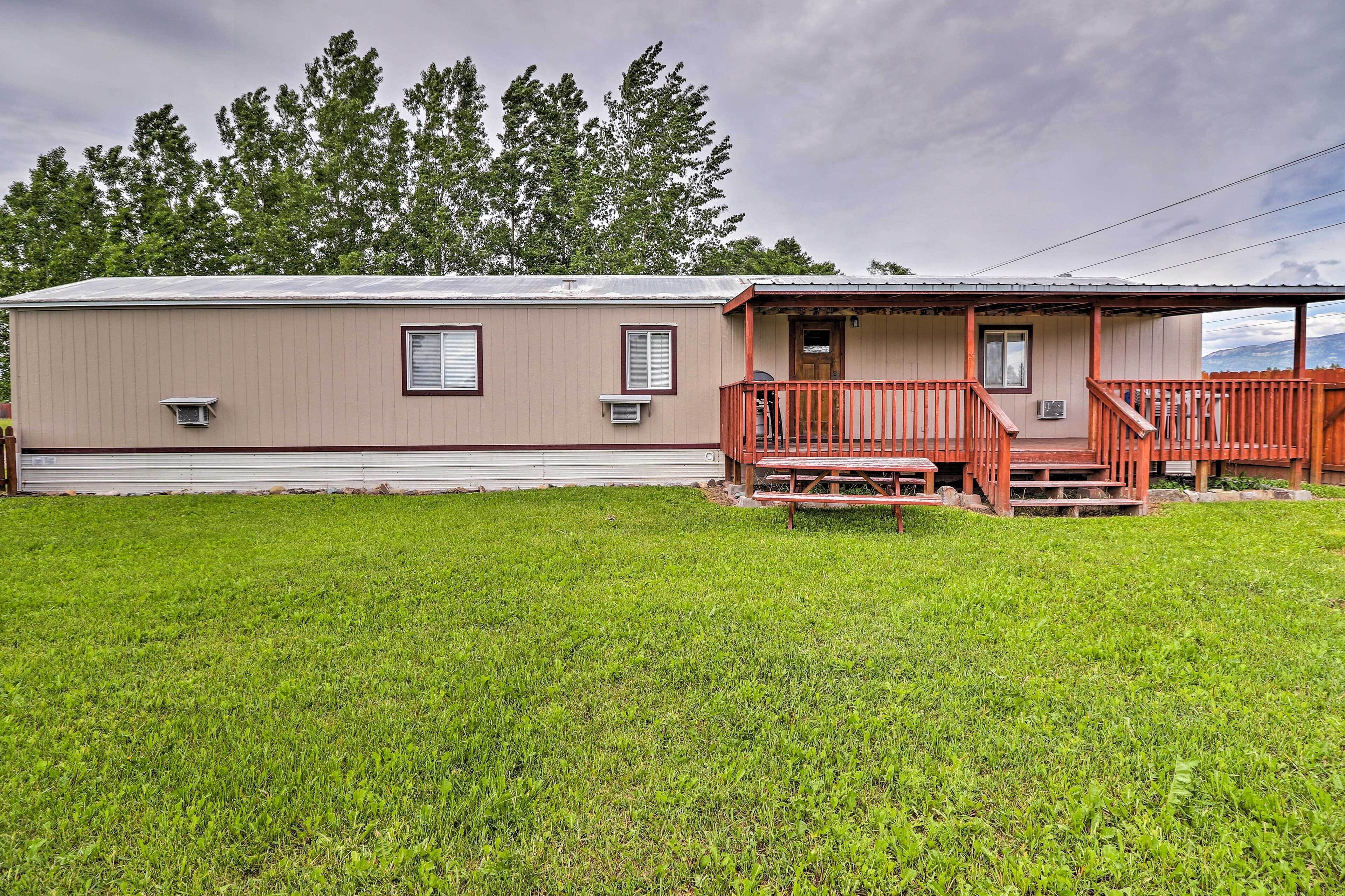 A two-story mobile home with a front porch and a small deck.