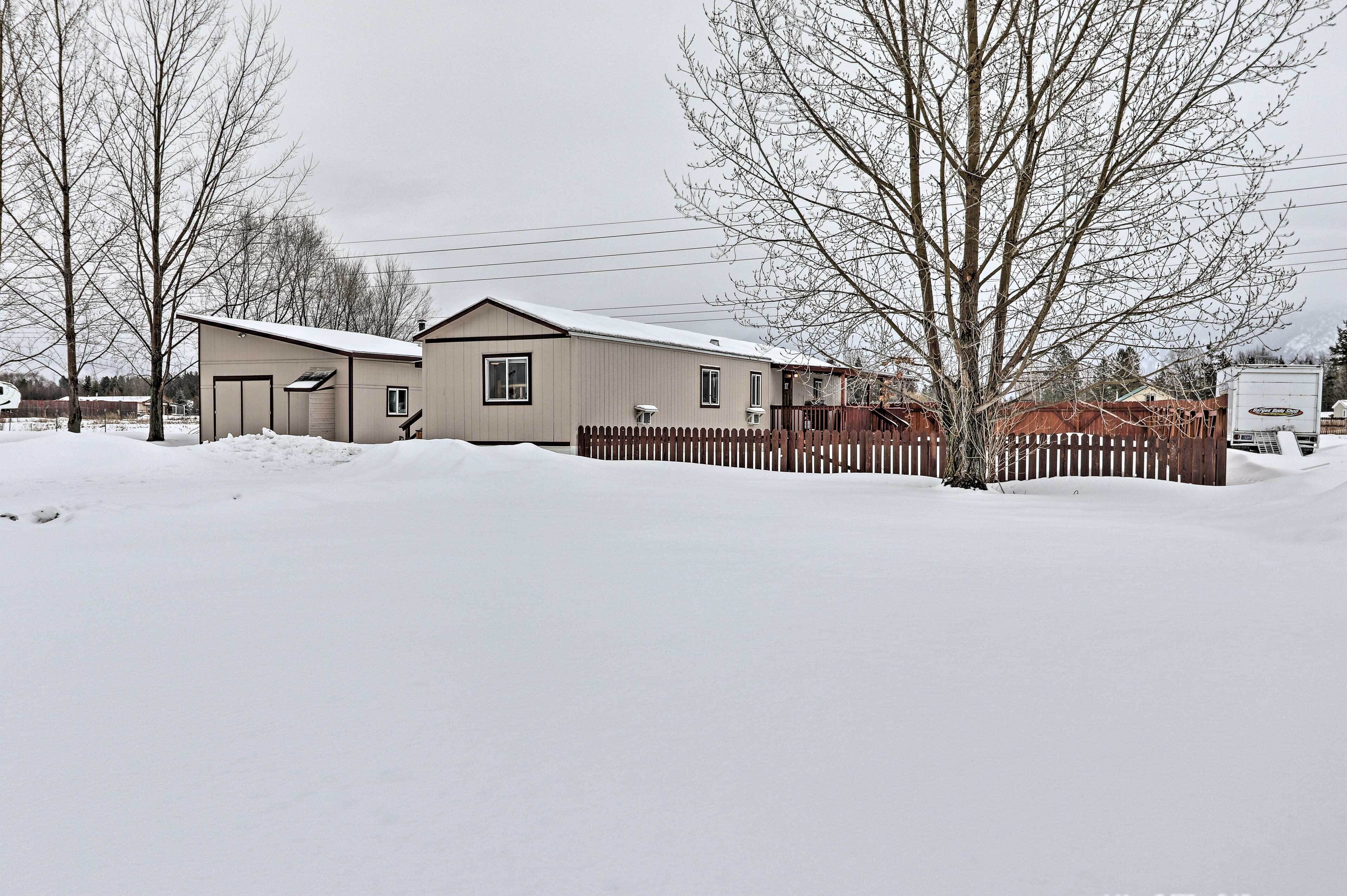 Une maison de plain-pied, avec un toit recouvert de neige et une clôture en bois.