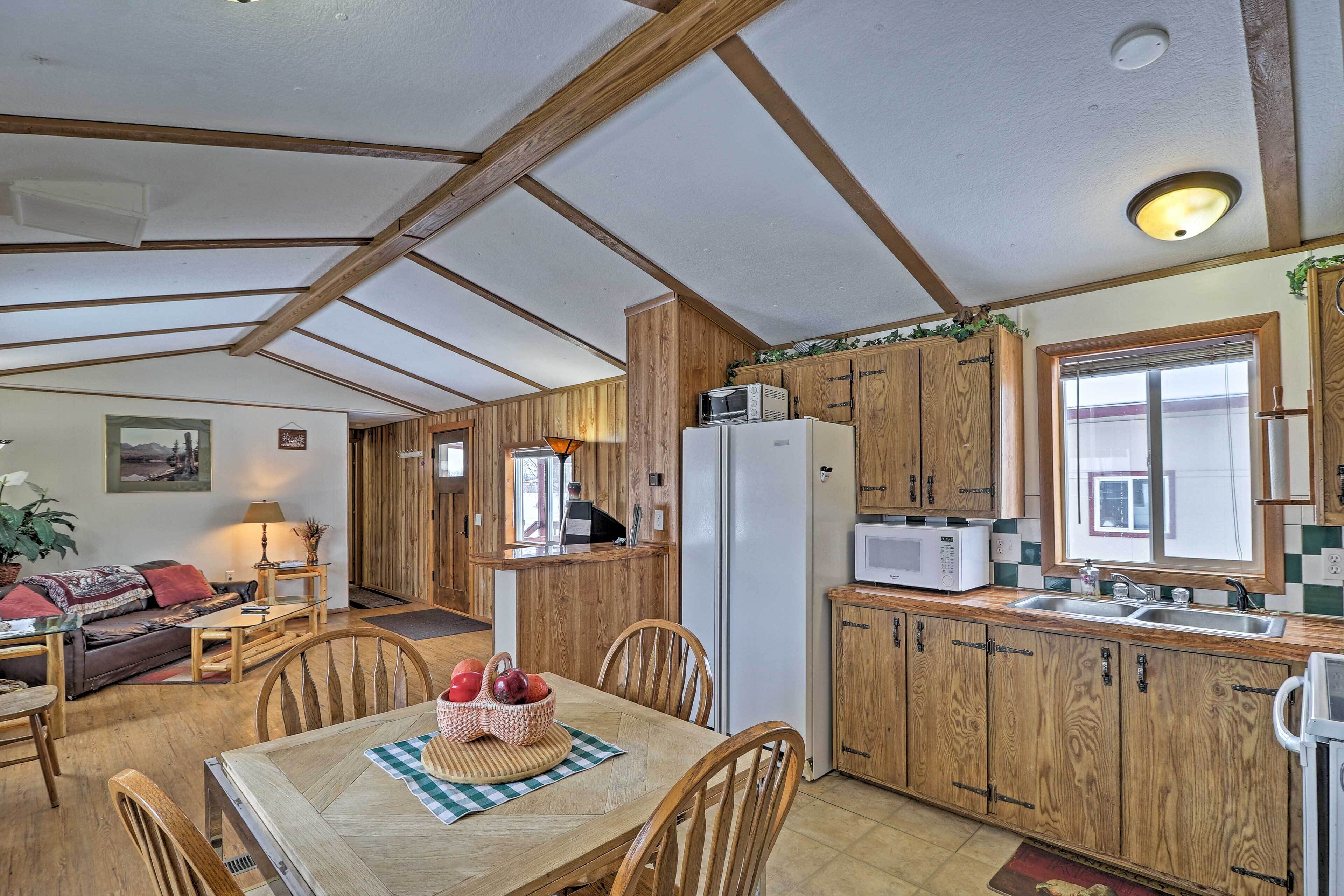 Une cuisine chaleureuse avec des meubles de rangement en bois, une table à manger avec des chaises, un réfrigérateur et un four à micro-ondes.
