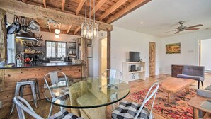 A modern kitchen with wooden beams, a glass dining table, and bar stools. - Charming Cottage w/ Yard - 2 Mi to Tinker St! (West Hurley)