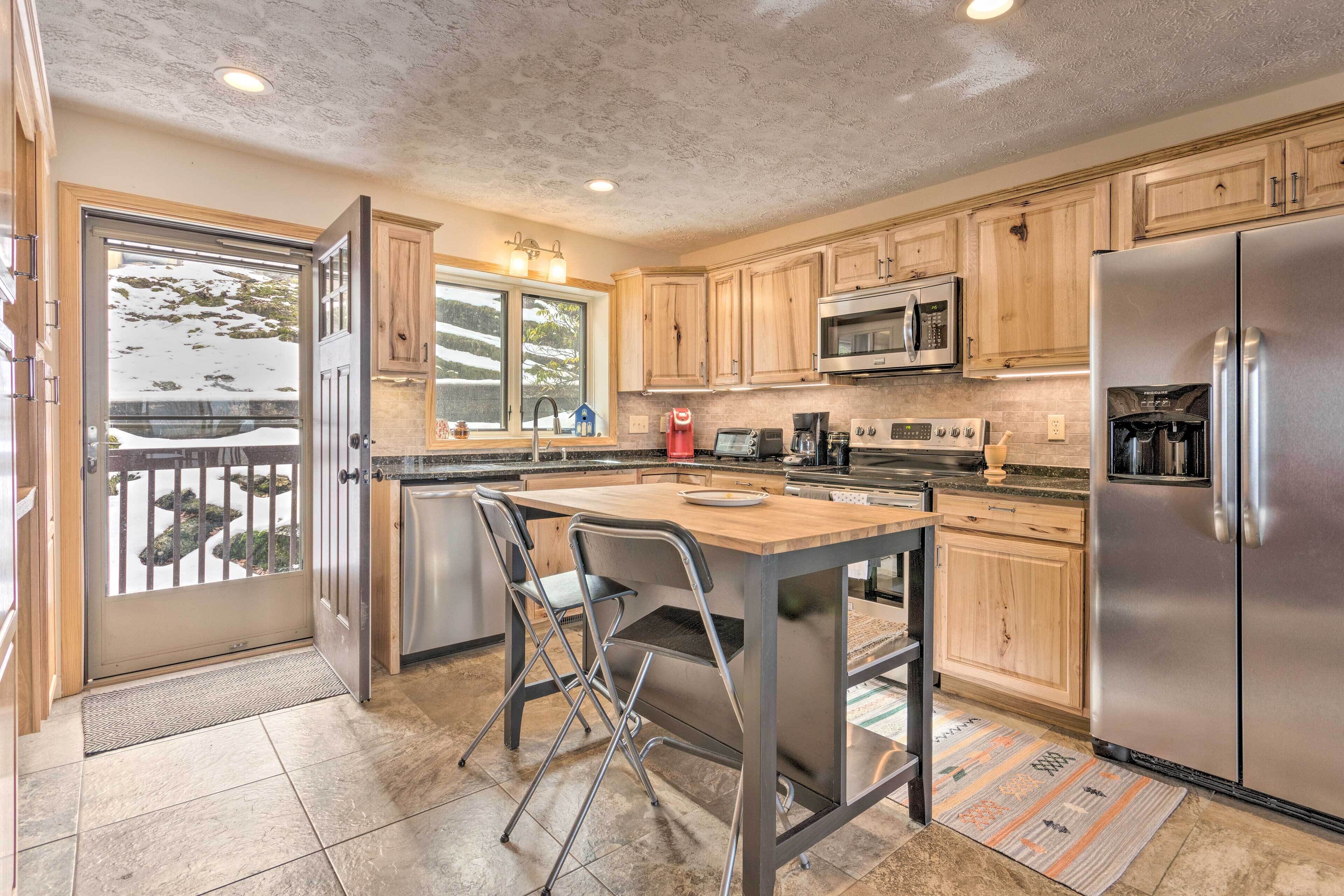 A modern kitchen with wooden cabinets, stainless steel appliances, and a large island with bar stools.