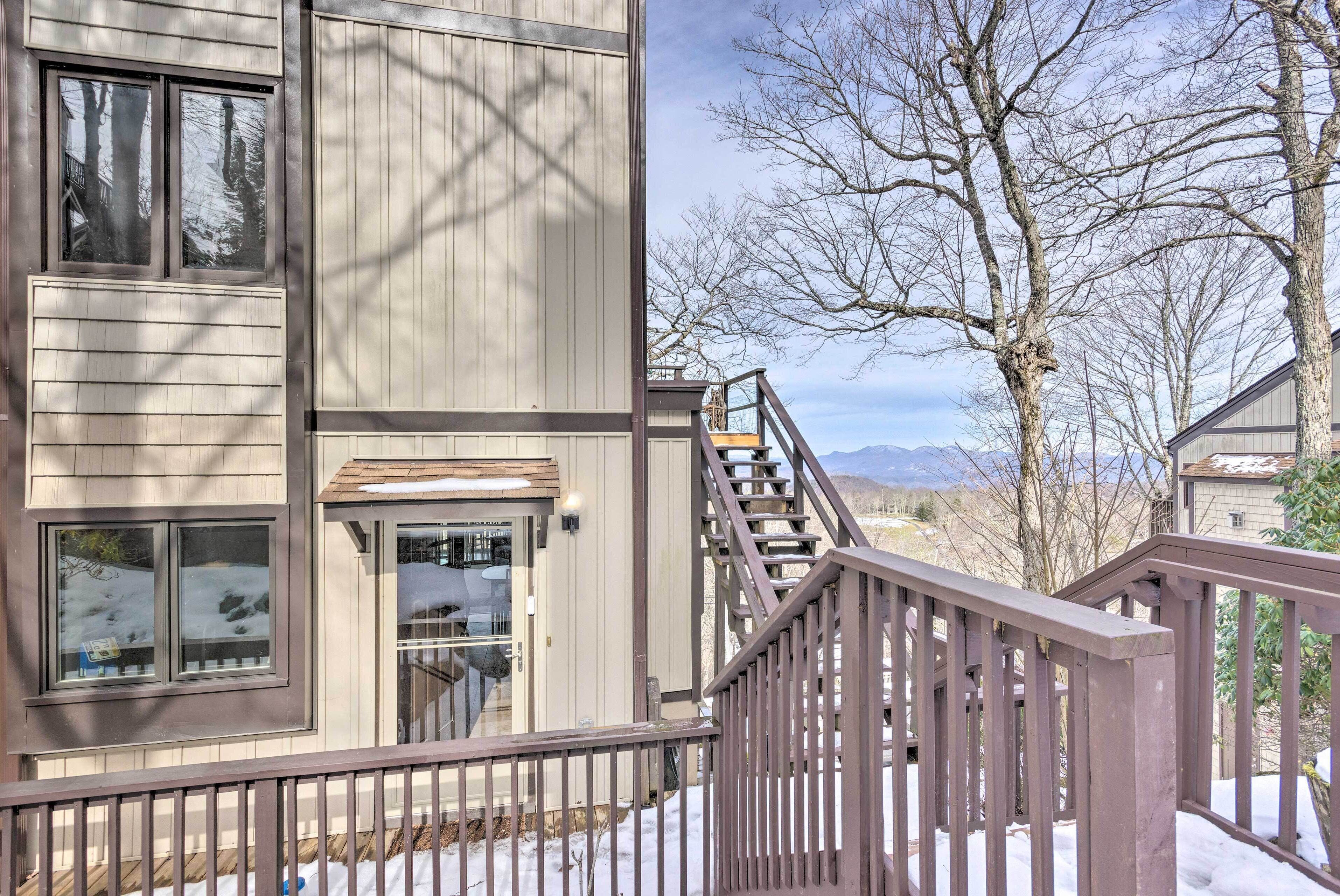 Un bâtiment à deux étages, avec une façade en bois, un escalier apparent et une vue sur les montagnes en arrière-plan.