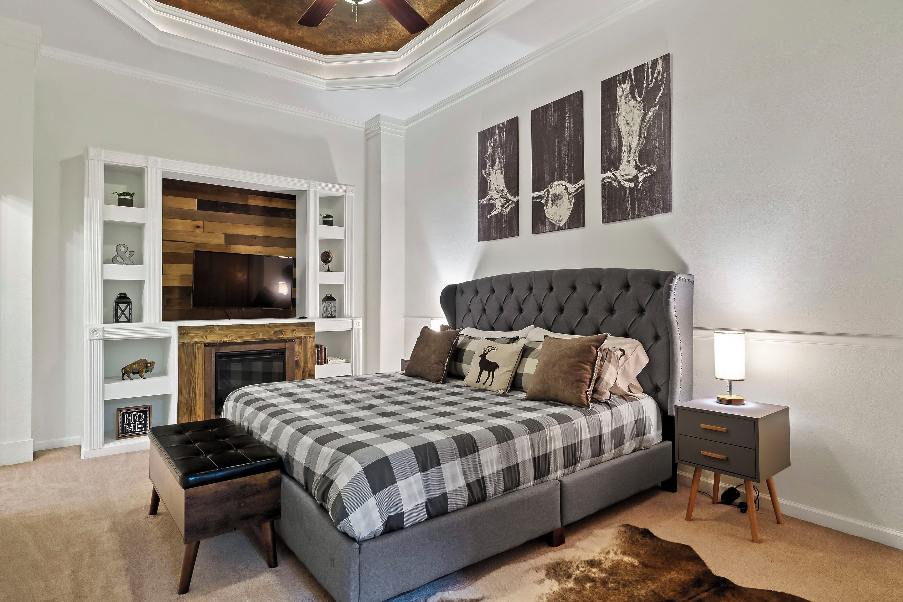 A bedroom with a large bed, a TV, a fireplace, and a storage unit.