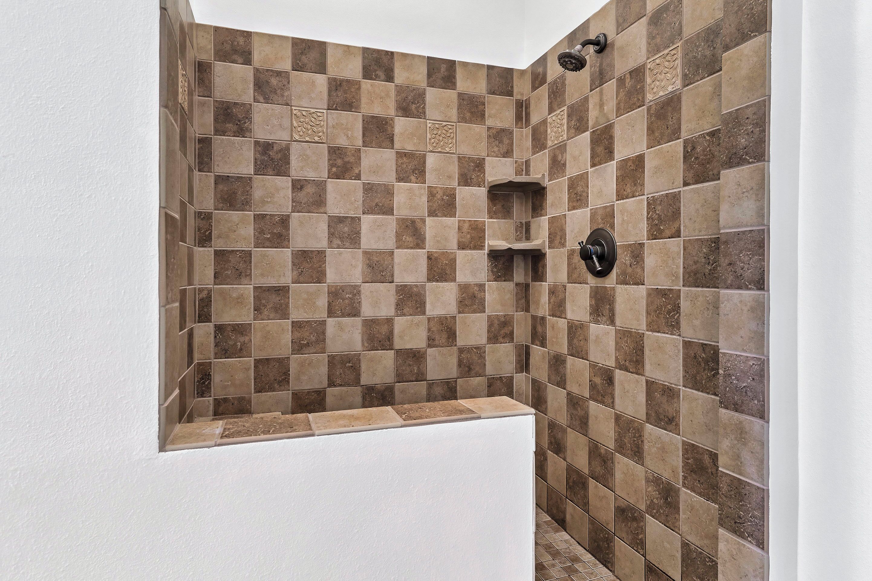 Un espace douche avec un mur carrelé à motifs à carreaux et une baignoire blanche.