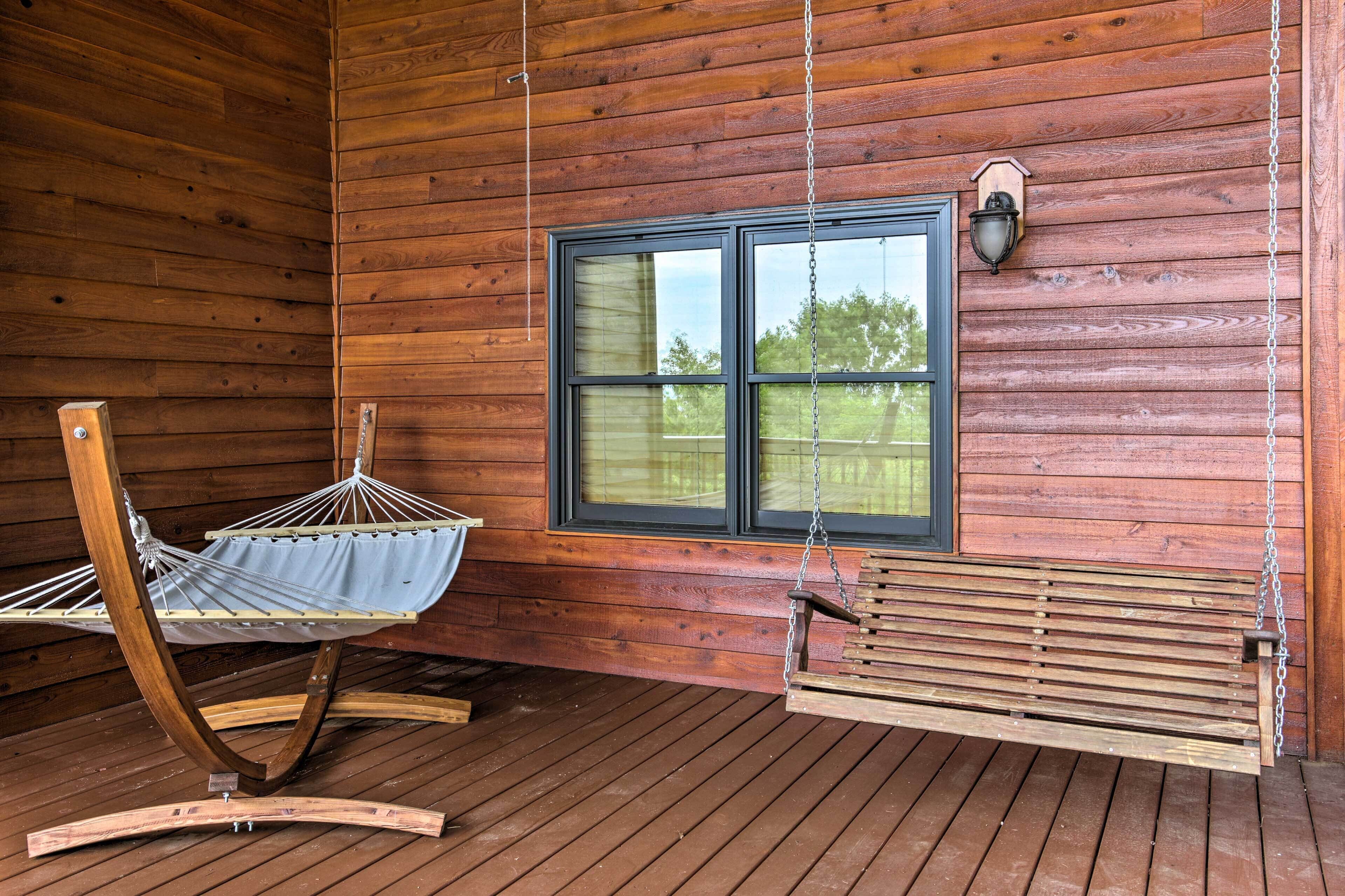 A wooden cabin with a porch, a hammock, and a bench.