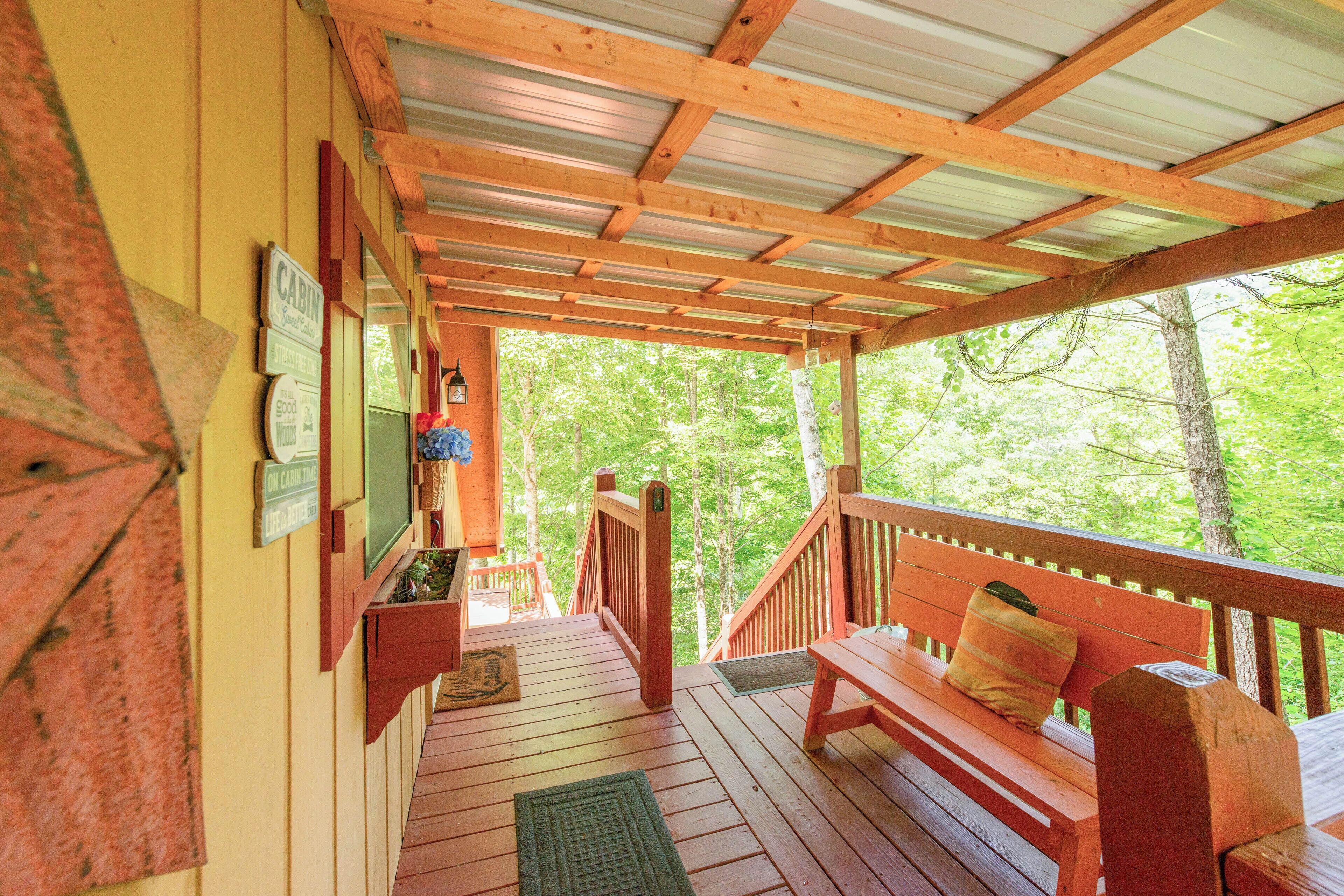 A wooden deck with a bench and a view of a forest.