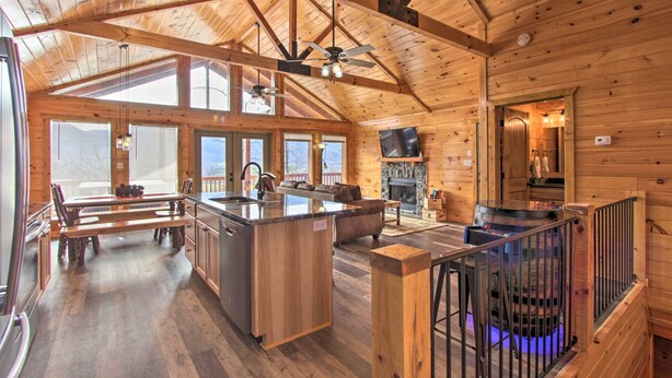 Une cabane en bois spacieuse, dotée d’un grand espace repas, d’une cuisine et d’une cheminée.