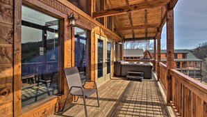 Une terrasse en bois avec un barbecue et un espace salon, de grandes fenêtres et une vue sur une montagne.