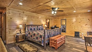 Une chambre dans une cabane en bois, avec un lit, une table de chevet, une lampe et une petite commode en bois.