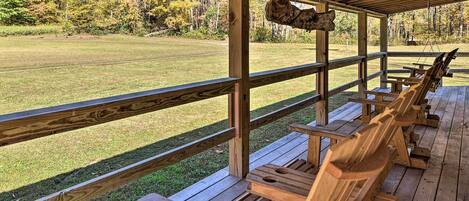 A covered wooden deck with benches and a rustic wooden sign.