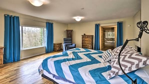 A bedroom with a large bed, a dresser, a chair, and a view of the outdoors through a window. - Charming Kelso Home w/ Proximity to Cowlitz River! (Kelso)