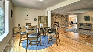 A dining area with a round table, chairs, and a blue rug. There is a stone wall and a wooden floor. - Charming Kelso Home w/ Proximity to Cowlitz River! (Kelso)