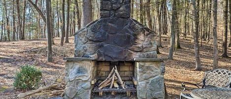 Chimenea de piedra con fuego, rodeada de un bosque.