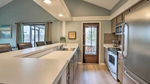 A modern kitchen with a large island, stainless steel appliances, and a view to the outside.