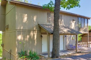 A two-story building with a covered porch, a large tree, and a small garden area.