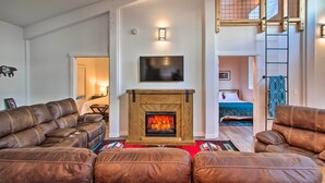 A living room with a fireplace, leather sofas, a TV mounted above the fireplace, and a staircase leading to an upper level. - Home w/ Hot Tub < 5 Miles to Rainier National Park (Mineral)