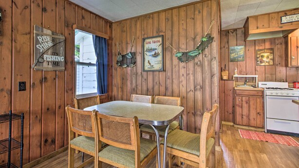 A wooden-paneled room with a dining table and chairs, a stove, and fishing-themed decorations. - Dent Cabin on Star Lake w/ Dock, Deck, Dining (Dent)