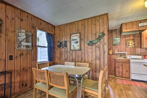 A wooden-paneled room with a dining table and chairs, a stove, and fishing-themed decorations. - Dent Cabin on Star Lake w/ Dock, Deck, Dining (Dent)