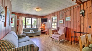 A cozy living room with a striped sofa, a pink armchair, and a wooden coffee table. - Dent Cabin on Star Lake w/ Dock, Deck, Dining (Dent)
