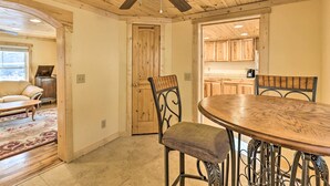 Un comedor con una mesa y sillas de madera, un ventilador de techo y armarios de madera al fondo.