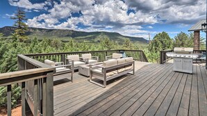 Eine Terrasse mit Gartenmöbeln, einem Grill und Blick auf die Berge.